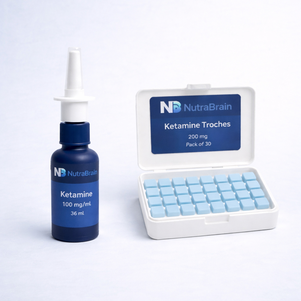 A bottle labeled "Ketamine 100 mg/mL" with a nasal spray top is next to an open case of "Ketamine Troches 200 mg," containing 30 light blue tablets.