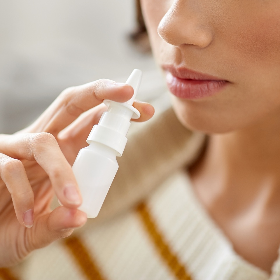 rhinitis, medicine and healthcare concept - close up of sick woman using nasal spray