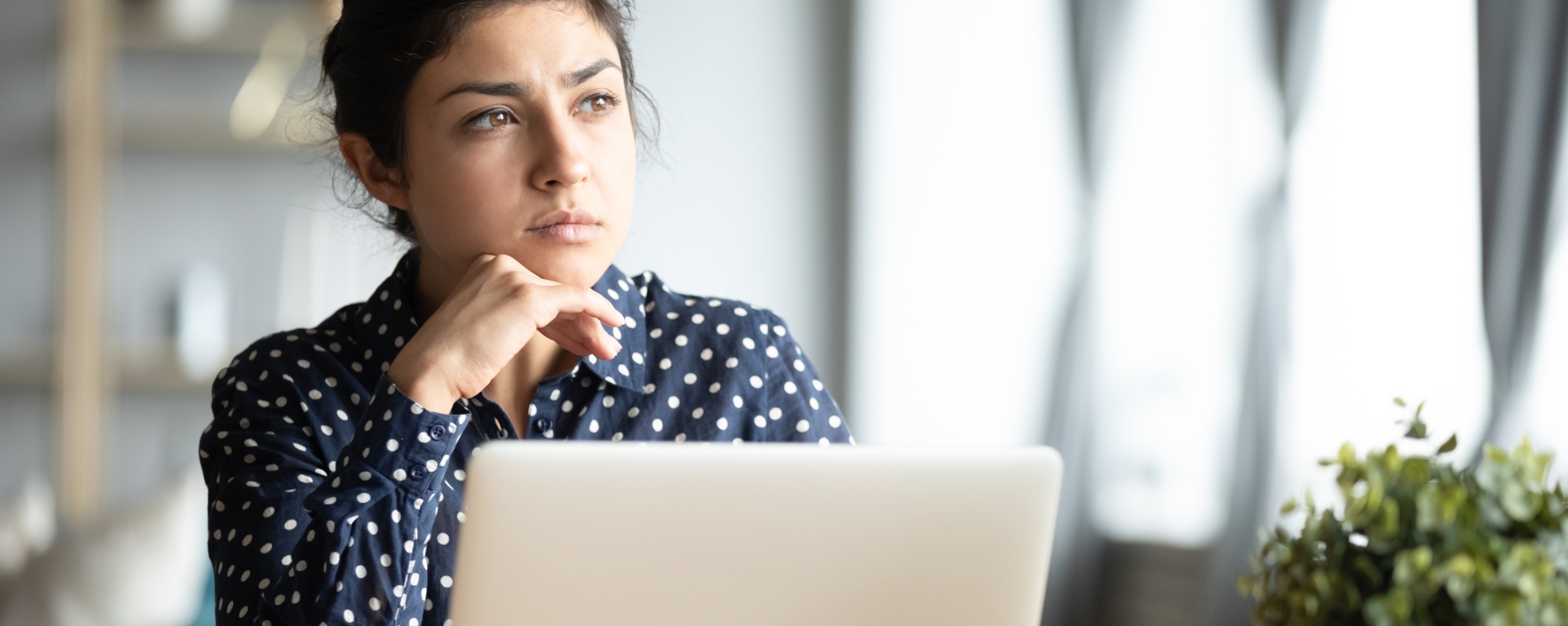 Serious thoughtful pensive young indian ethnic woman student sit at home office desk with laptop thinking of inspiration solution lost in thoughts dreaming looking away search creative ideas concept