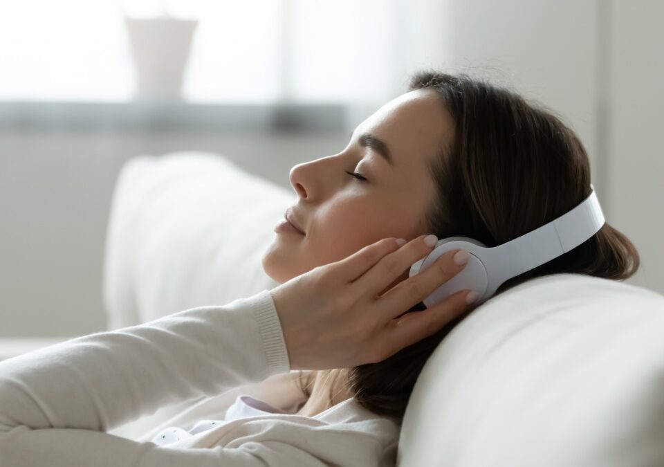 Calm female resting leaned on comfy couch in living room spend free time at home closed eyes enjoy music listening favourite song through wireless modern headphones. Pastime weekend relaxation concept