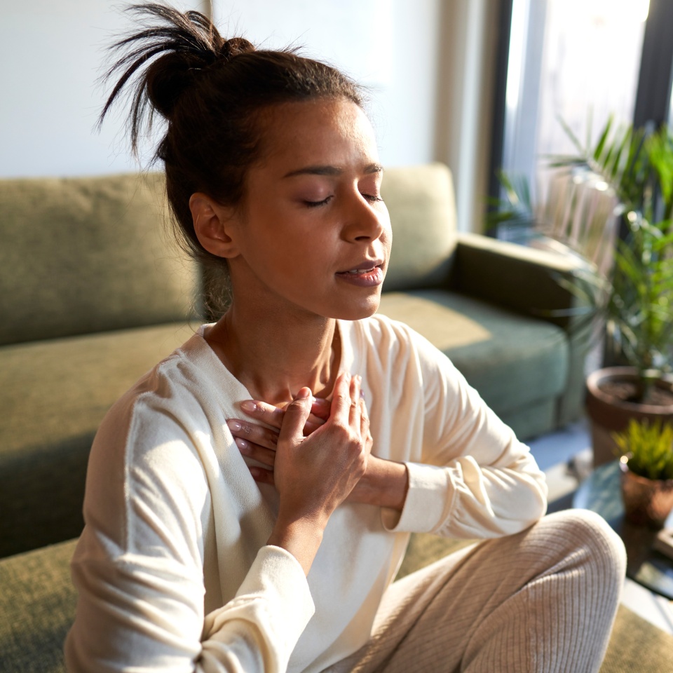 Woman meditating at home with eyes closed