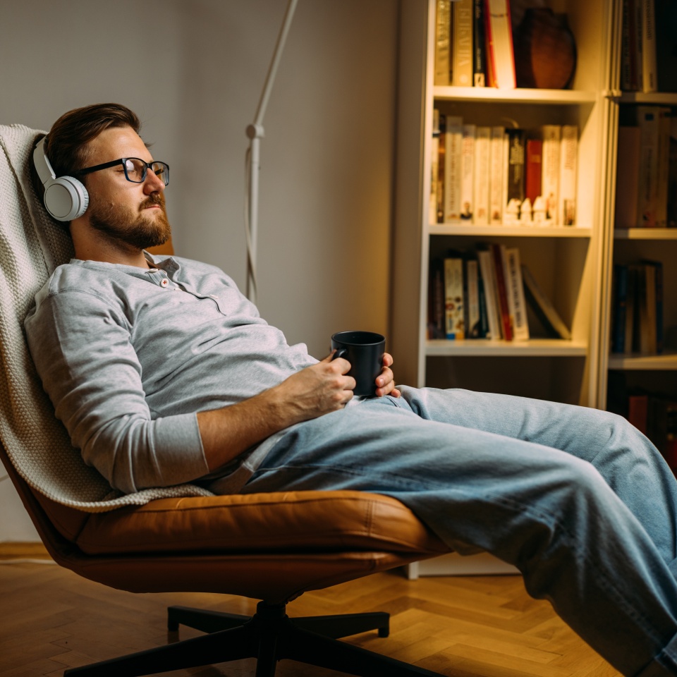 Caucasian man with eyes closed enjoying music with headphones while relaxing at home