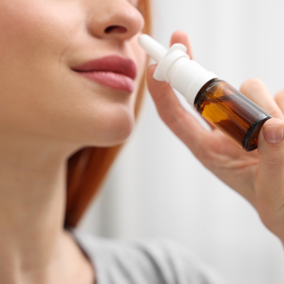 Medical drops. Woman using nasal spray at home, closeup
