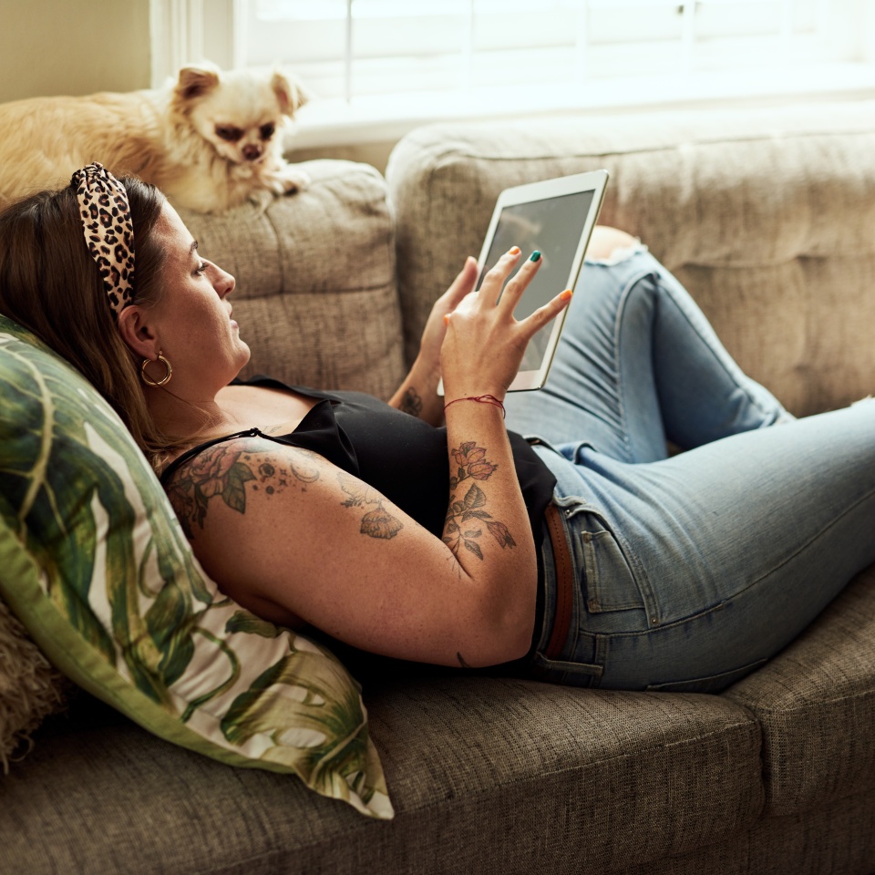 House, relax and woman on couch, tablet and internet with social media, texting and connection. Apartment, person and girl on sofa, technology and typing with message to contact and dog in lounge