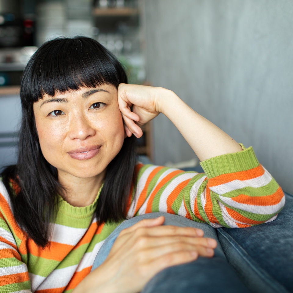 Portrait of a smiling Asian woman relaxing on a couch at home