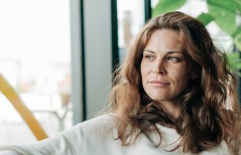 Relaxed woman sits on a sofa in a bright modern cafe with potted plants