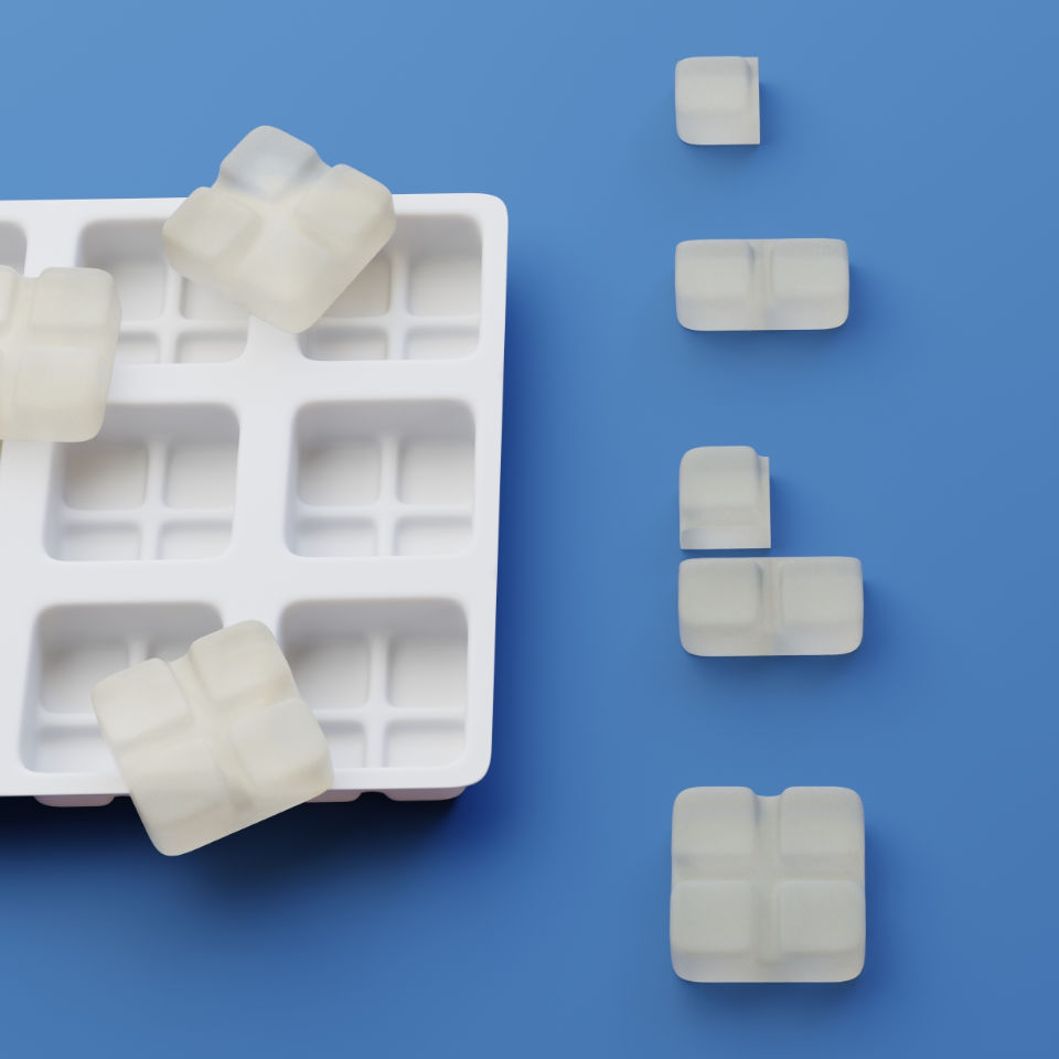 A white ice cube tray with several opaque cubes is tipped on a blue surface, with some cubes aligned in a row leading away from the tray.