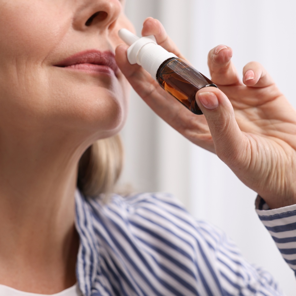 Medical drops. Woman using nasal spray indoors, closeup